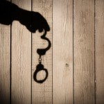 Male Hand with Handcuffs on Natural Wood Background, XXXL.